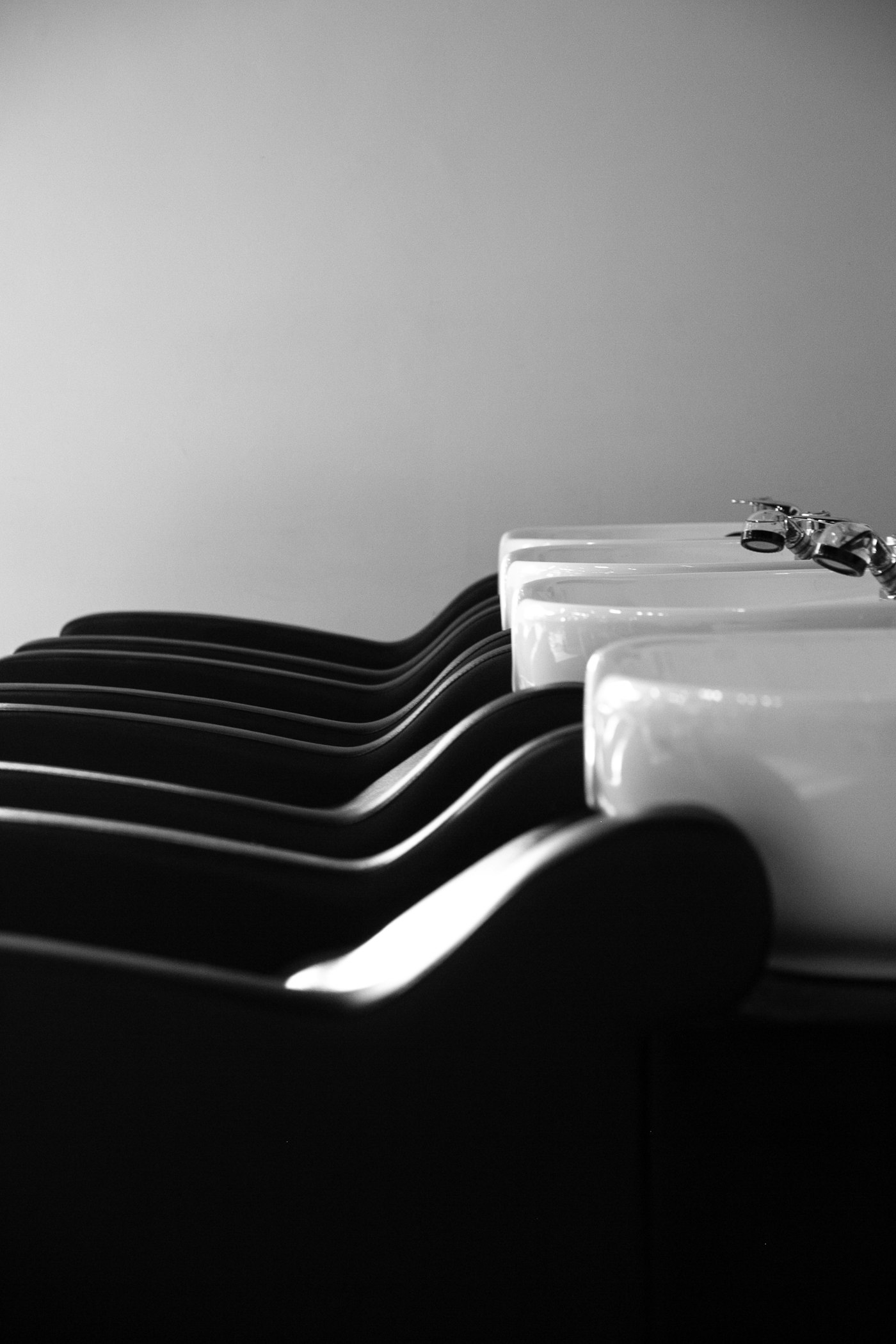 Row of black wash basins photographed in high-contrast black and white
