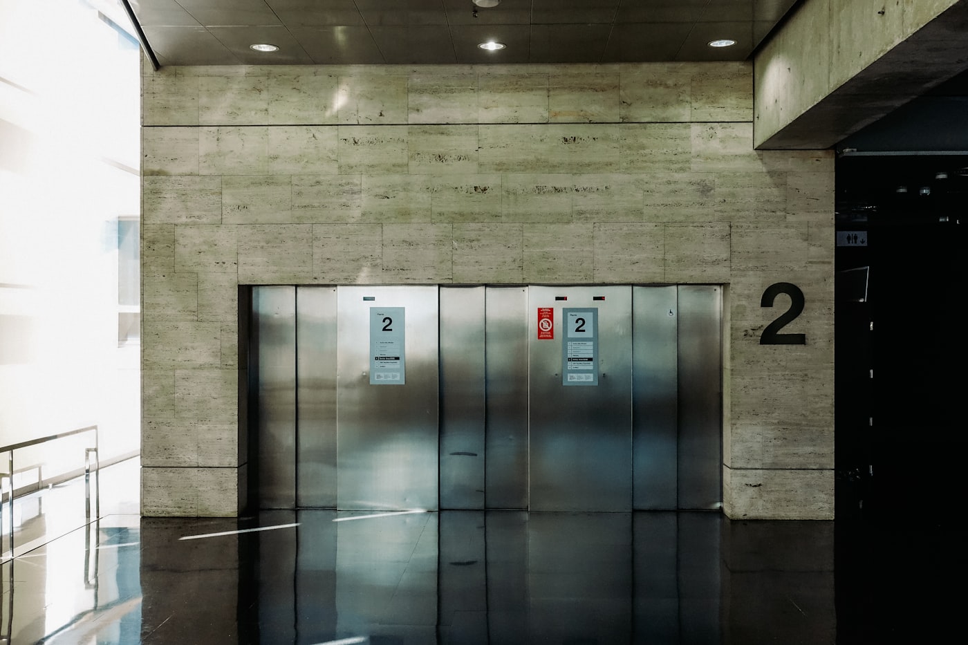Concrete lobby of the Mateo Street building with a steel lift door and a painted number two