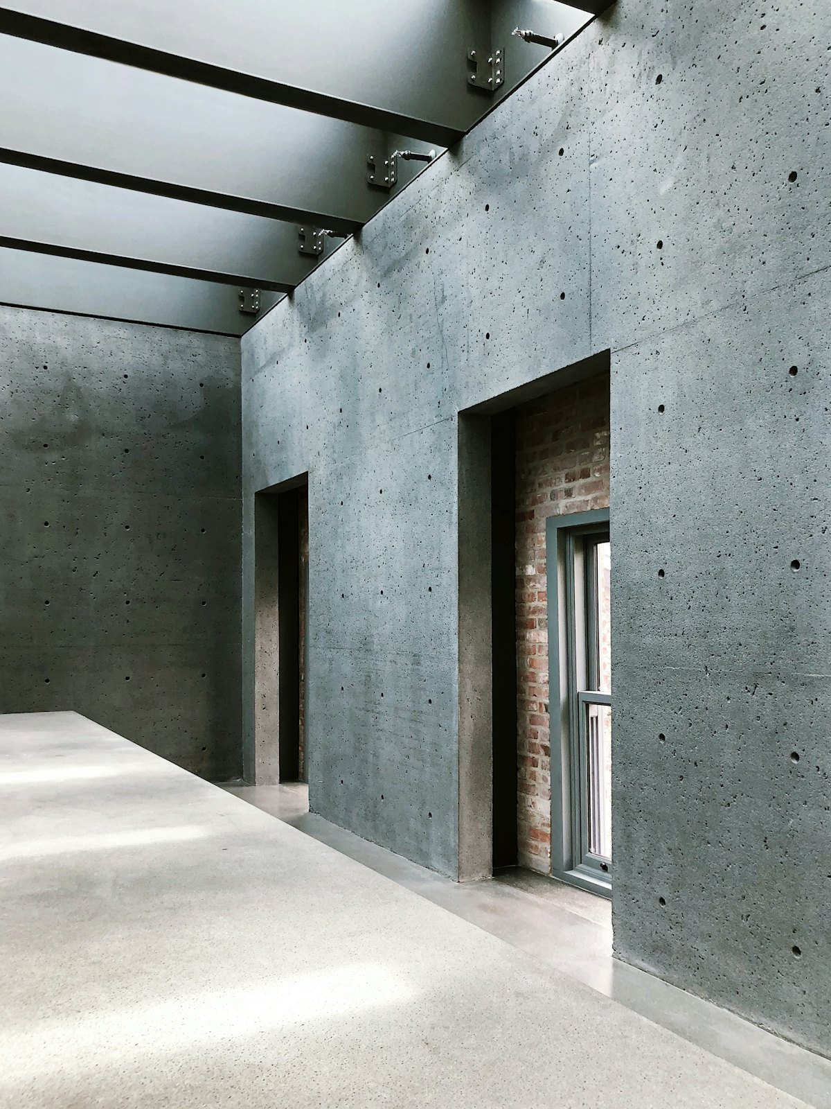 Board-marked concrete wall with a steel-framed opening cut into it