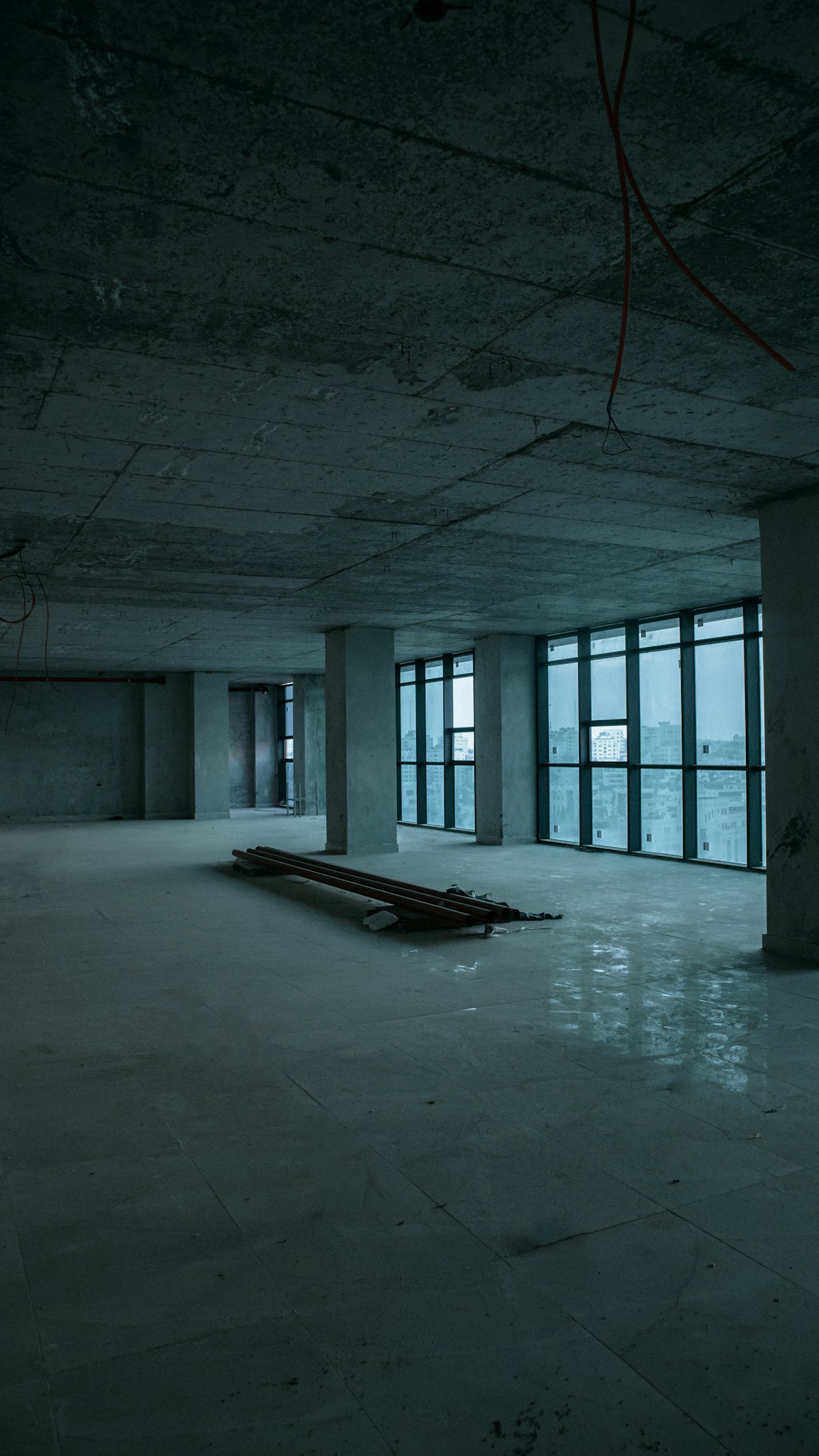 Raw unfinished concrete shell with steel columns and a bank of windows