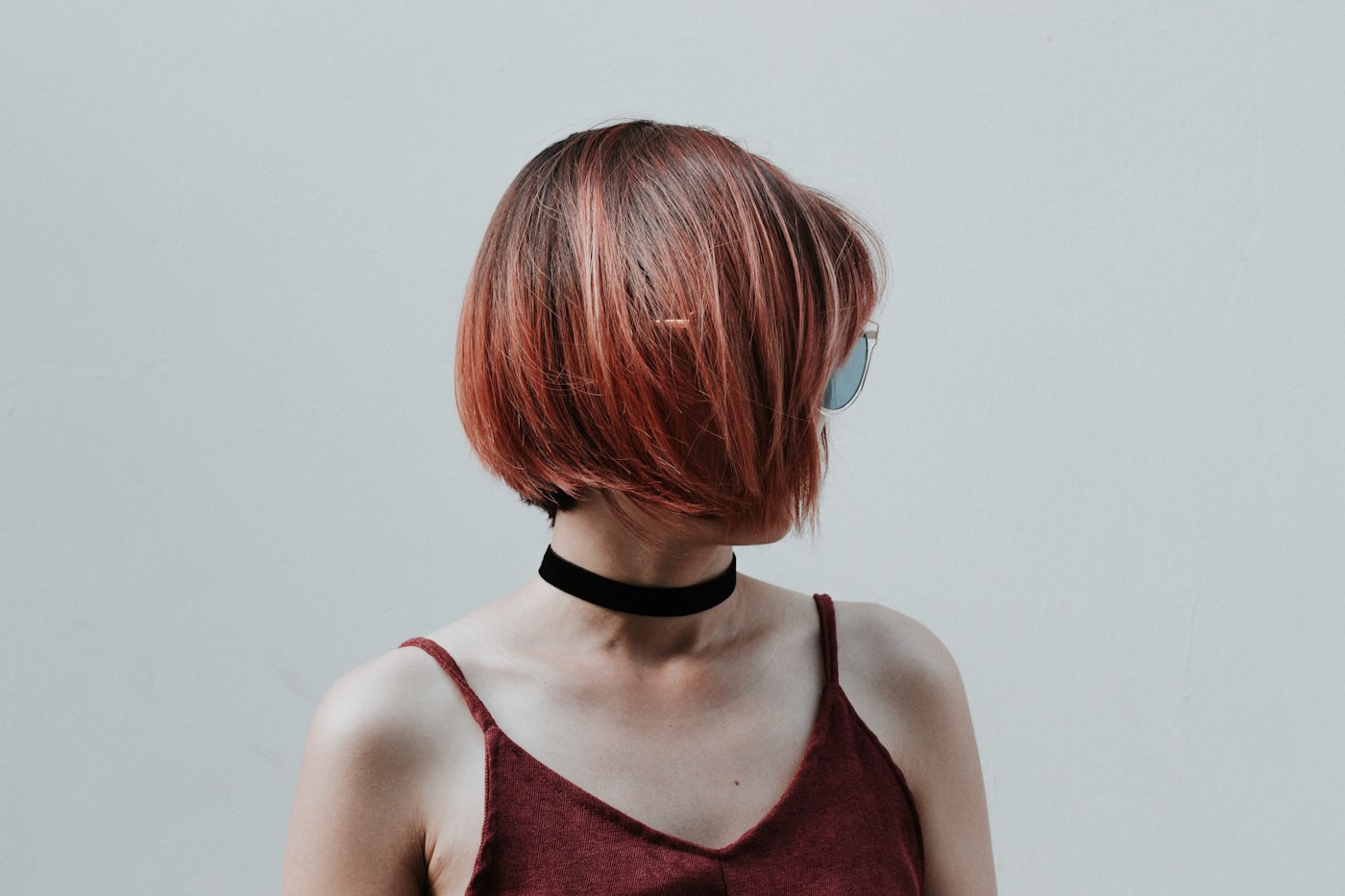 Studio portrait of a client with a copper blunt bob cut to a hard perimeter, shot against a plain wall