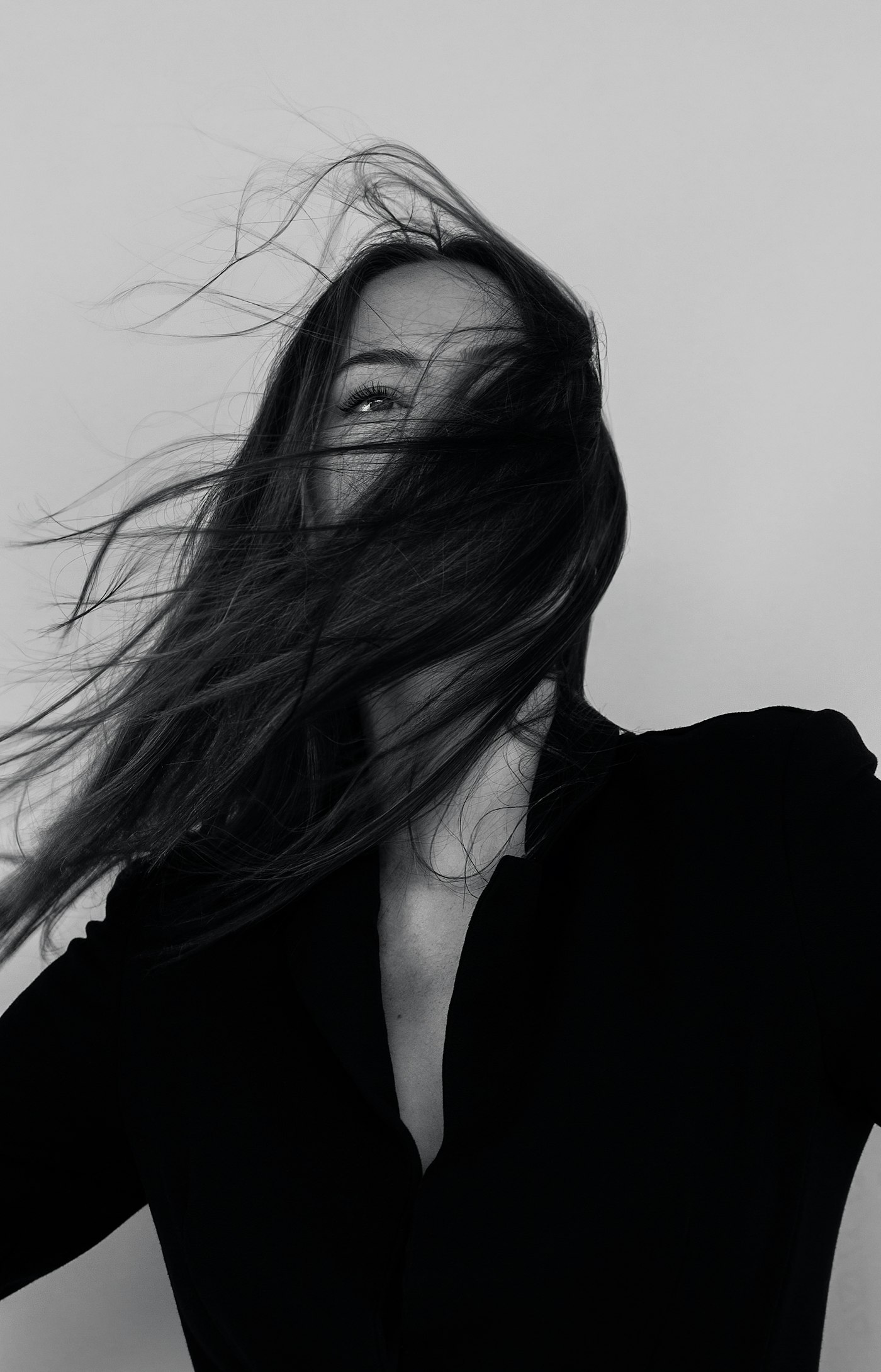 Black and white frame of long dark hair caught mid-movement against a plain background